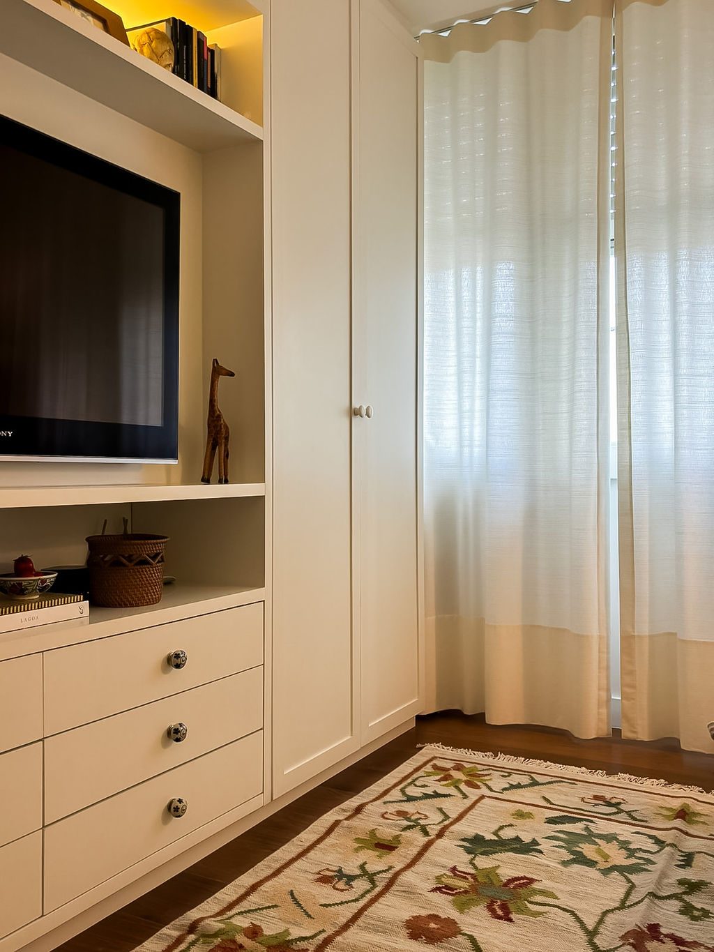 Armário com TV embutida e cortina clara