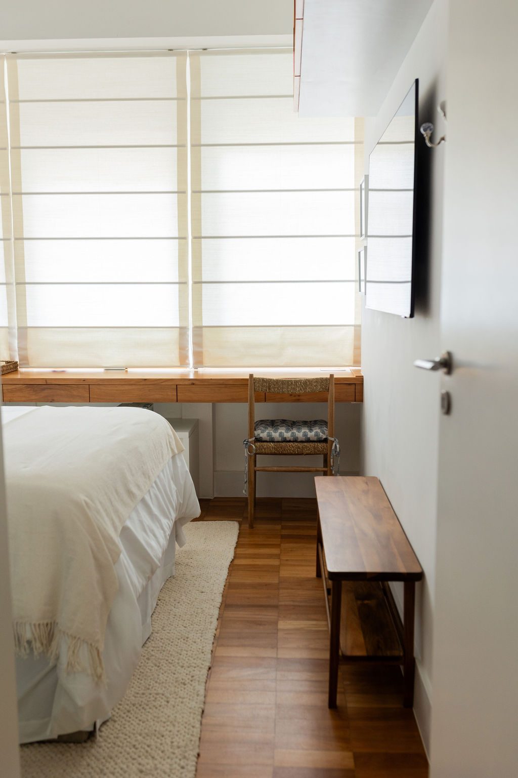 Quarto com cortina romana e banco de madeira