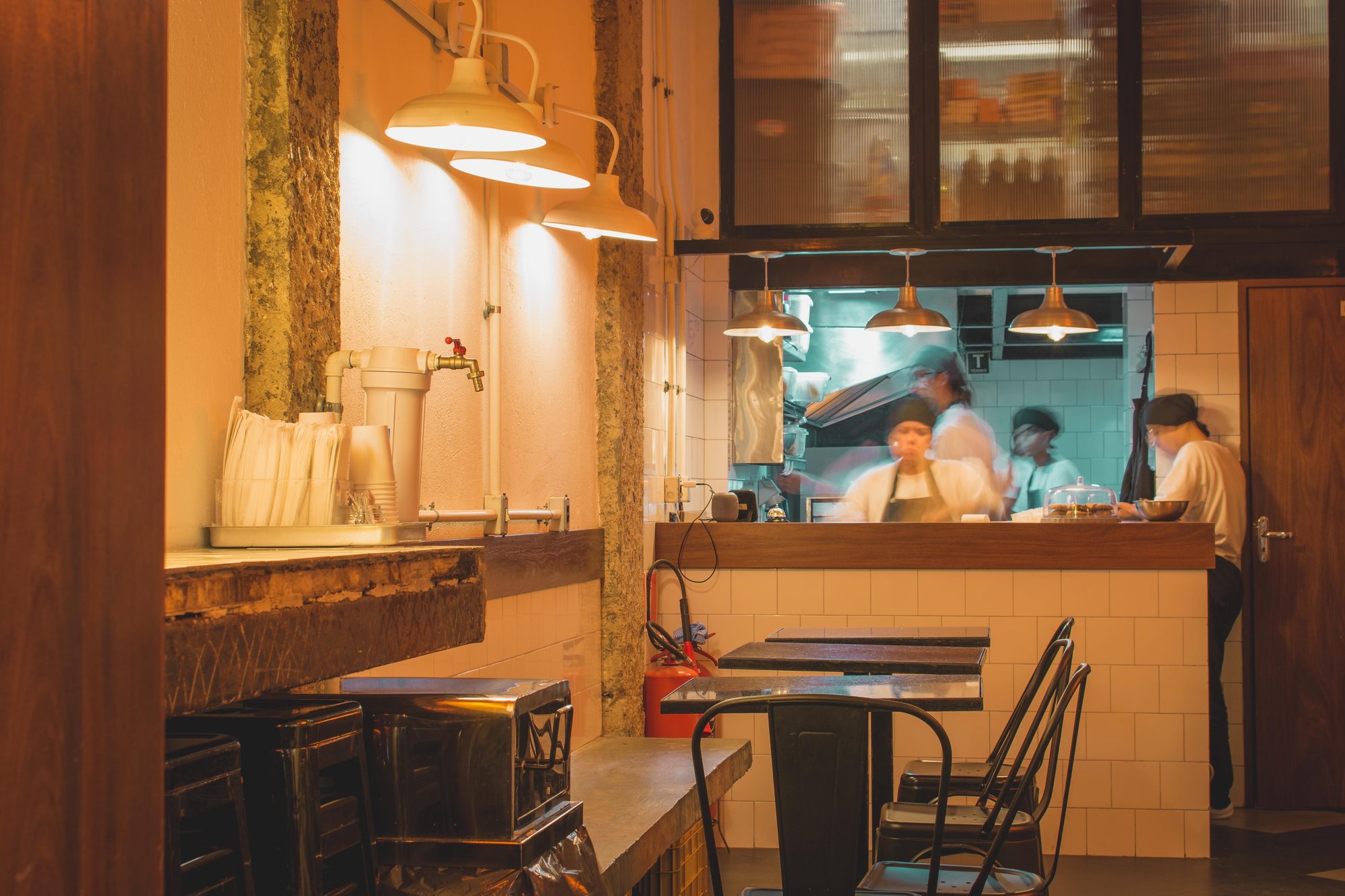 Balcão e cozinha aberta com luminárias pendentes