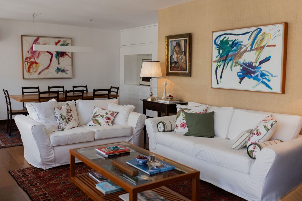 Sala de estar com sofás brancos e quadros coloridos