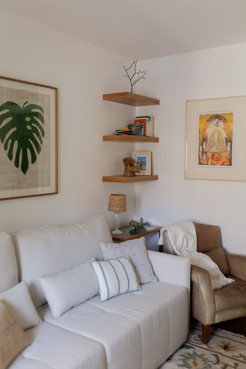 Sala de TV com sofá bege, nichos e quadros