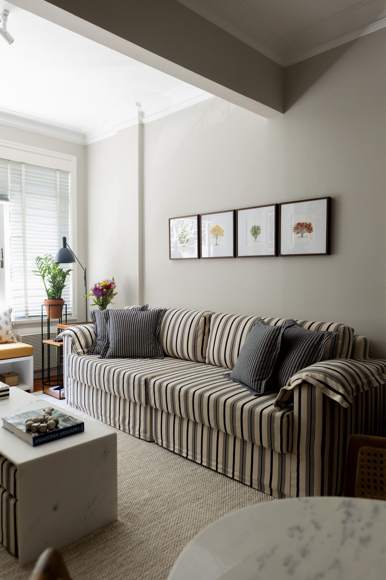 Sala de estar com sofá listrado e quadros botânicos
