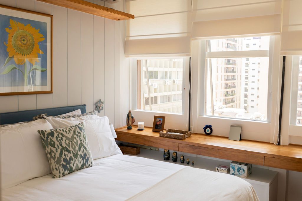 Quarto de casal com cabeceira azul e bancada sob a janela