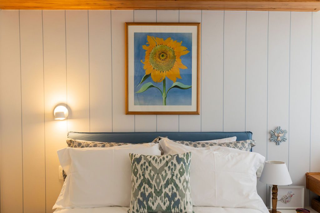 Cama de casal com quadro de girassol e arandelas