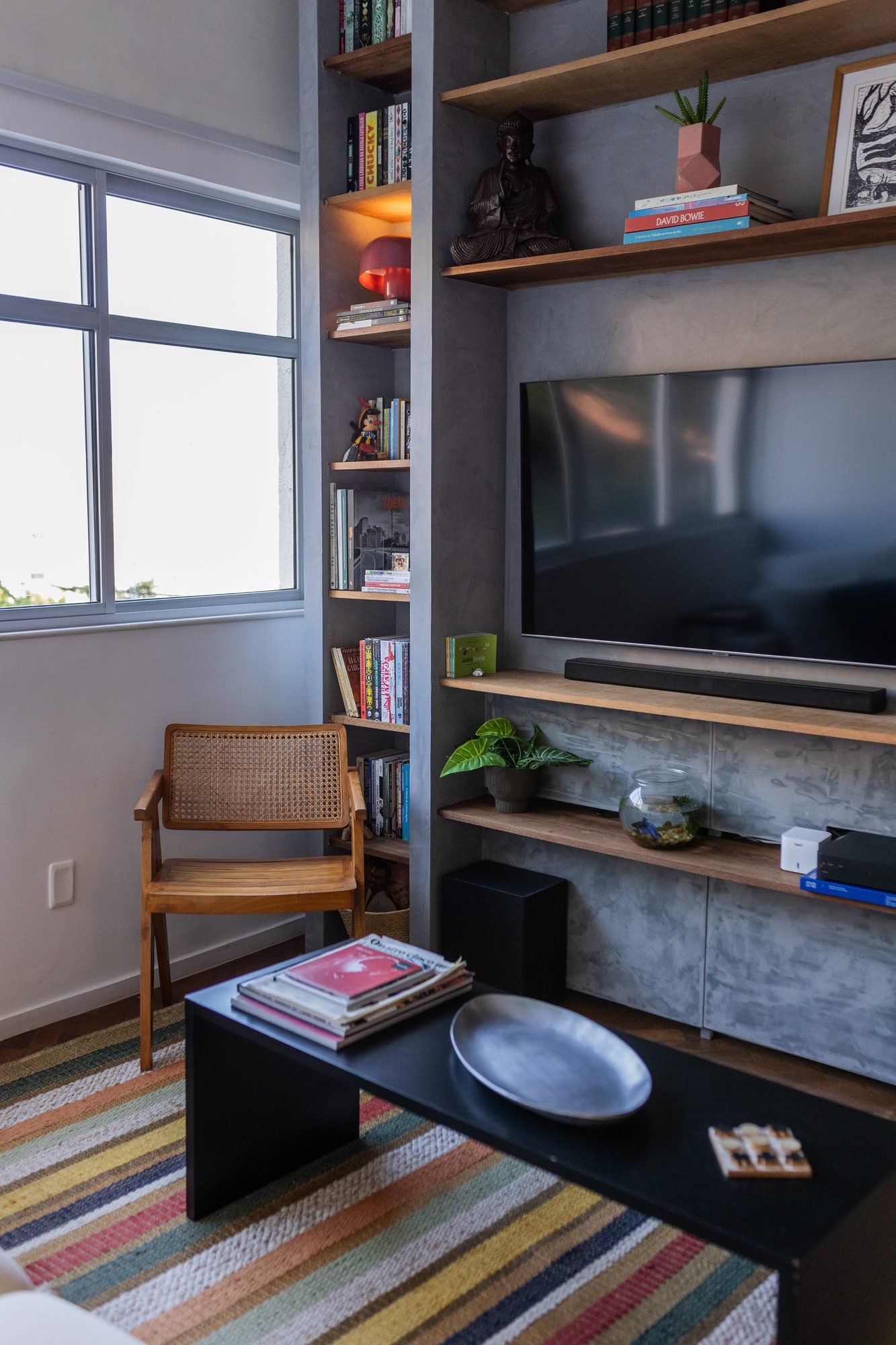 Sala de TV com estante de concreto e poltrona de palhinha