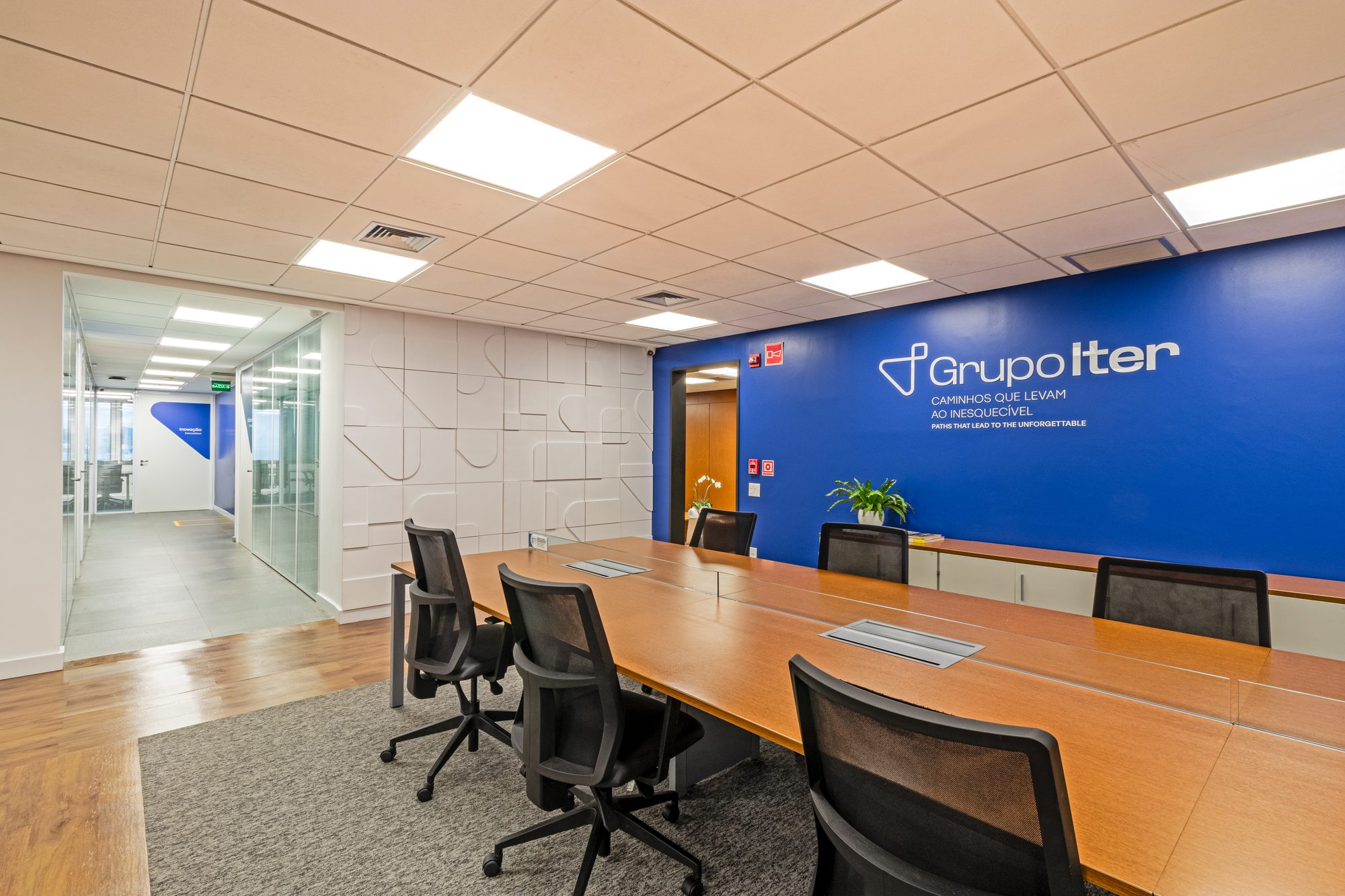 Sala de reunião com mesa longa e parede azul com logotipo