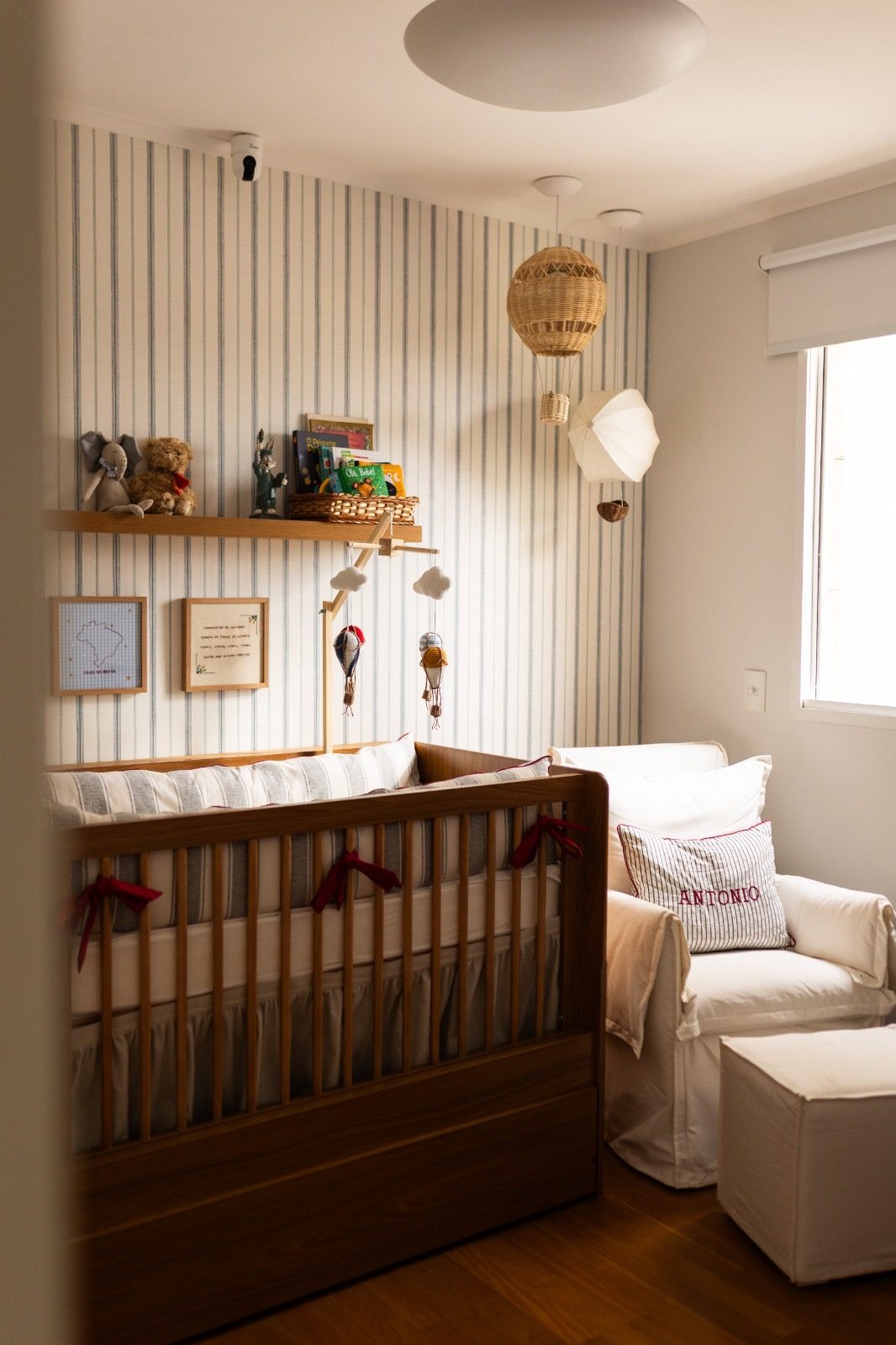 Quarto de bebê com berço, poltrona e luminária de teto