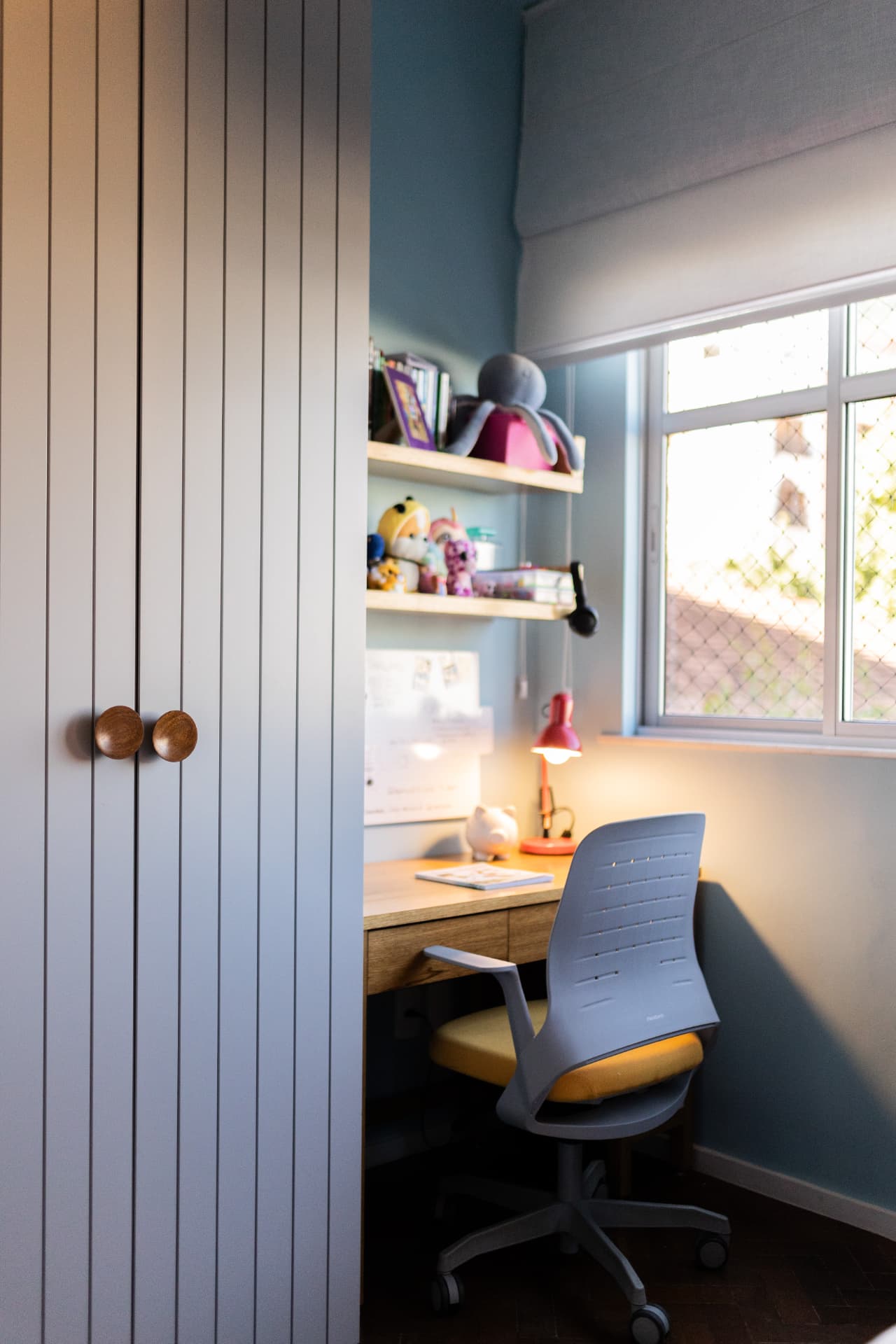 Home office azul integrado a armário com portas ripadas