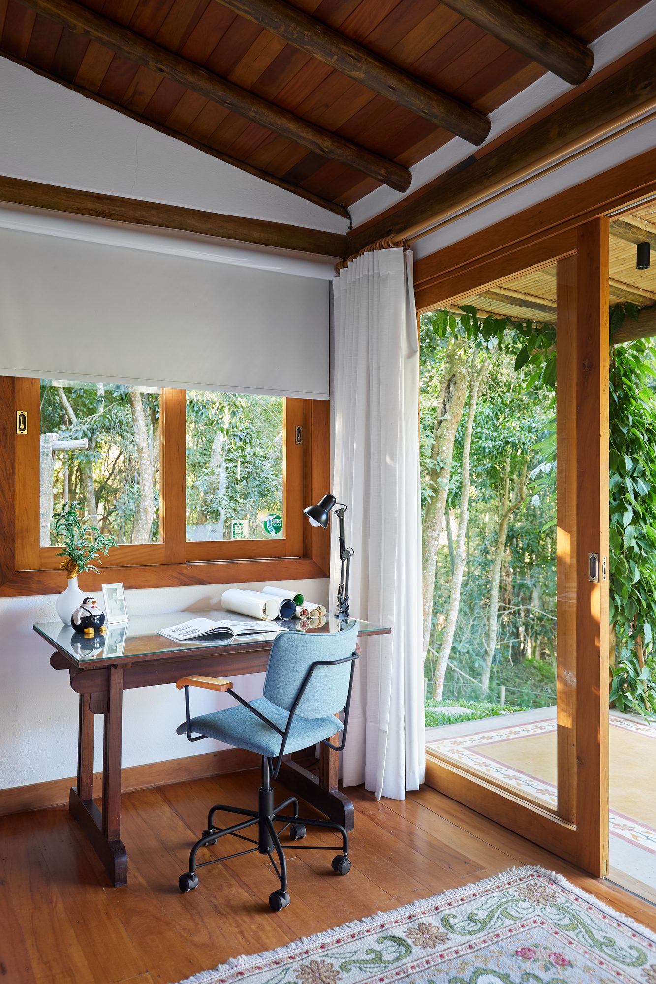 Escritório com mesa junto à janela e cadeira azul