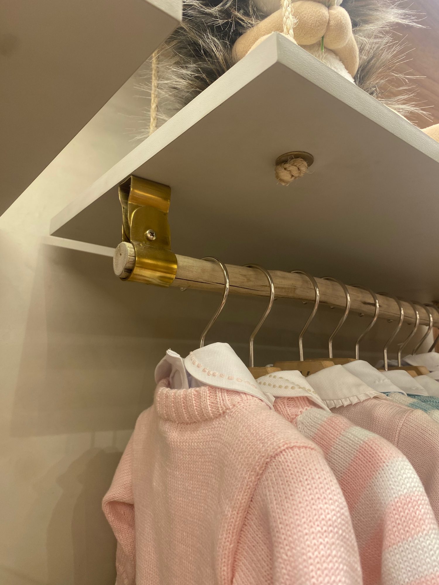 Arara de latão com roupas infantis em tons de rosa